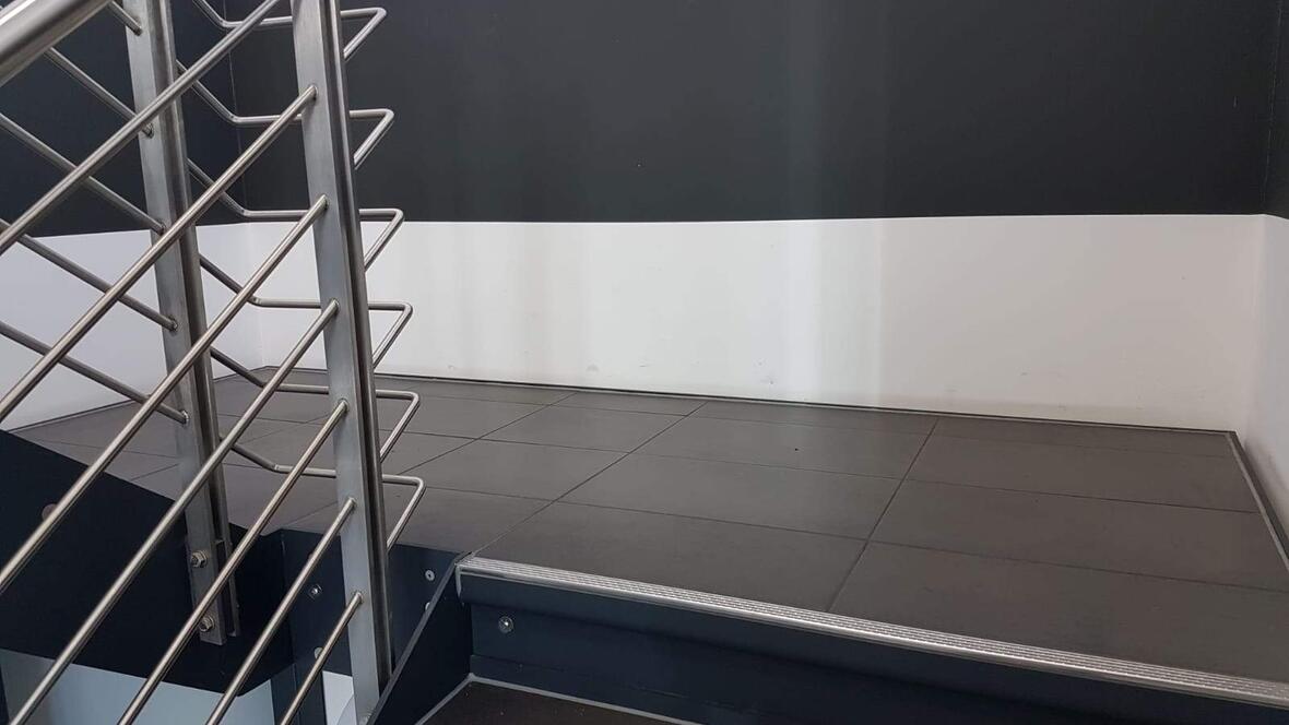 treppengelaender-silber-und-treppenstufen-aus-schwarzen-fliesen